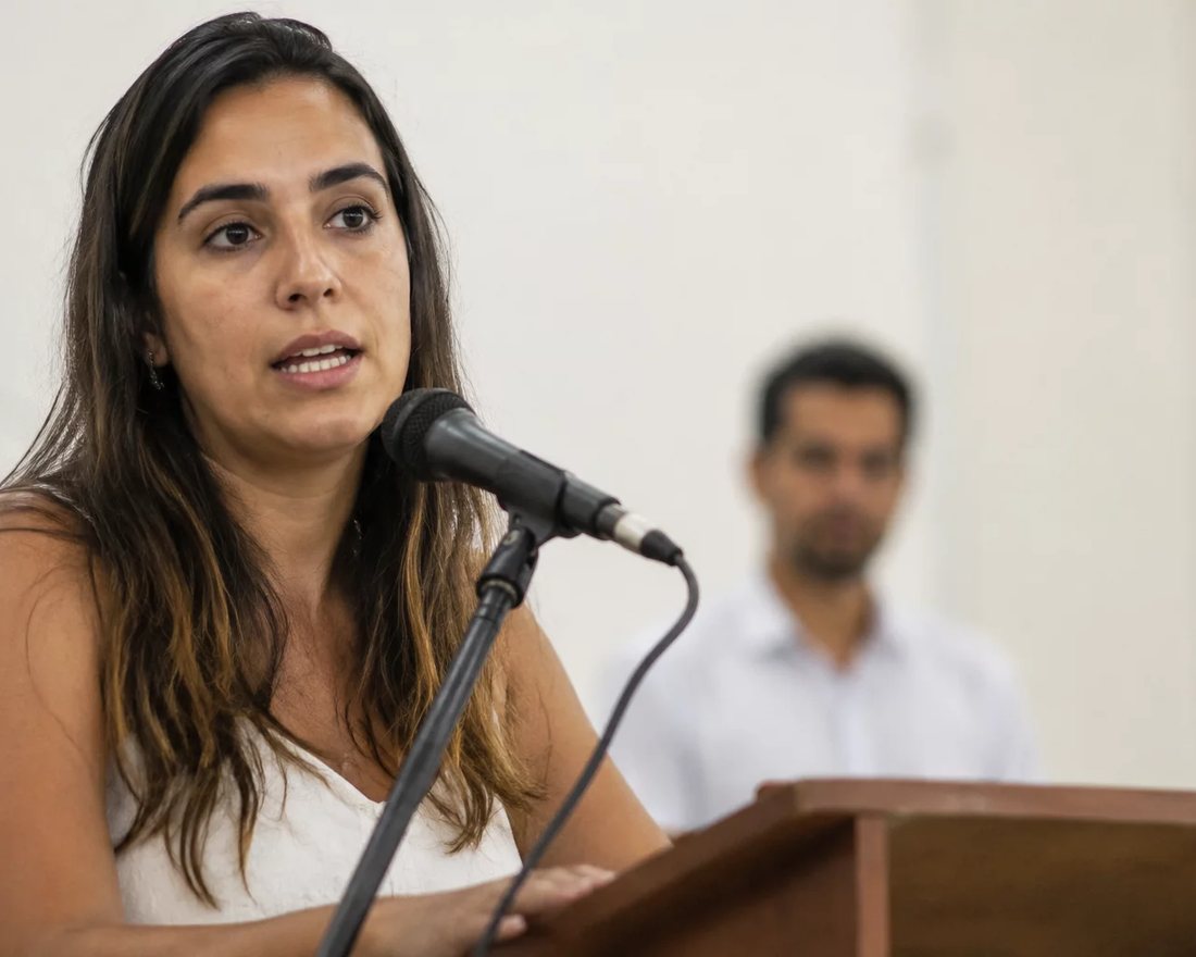 Participante ergue a mão para pedir a palavra numa mesa coberta de folhas anotadas